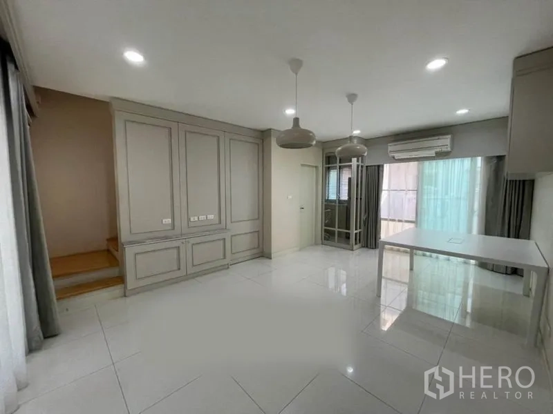 ทาวน์เฮาส์ ขายในSuan Luang, Bangkok - ห้องนั่งเล่นโปร่งสว่าง พร้อมตู้บิวท์อิน โคมแขวน และประตูกระจก ในทาวน์เฮาส์ย่านสวนหลวง