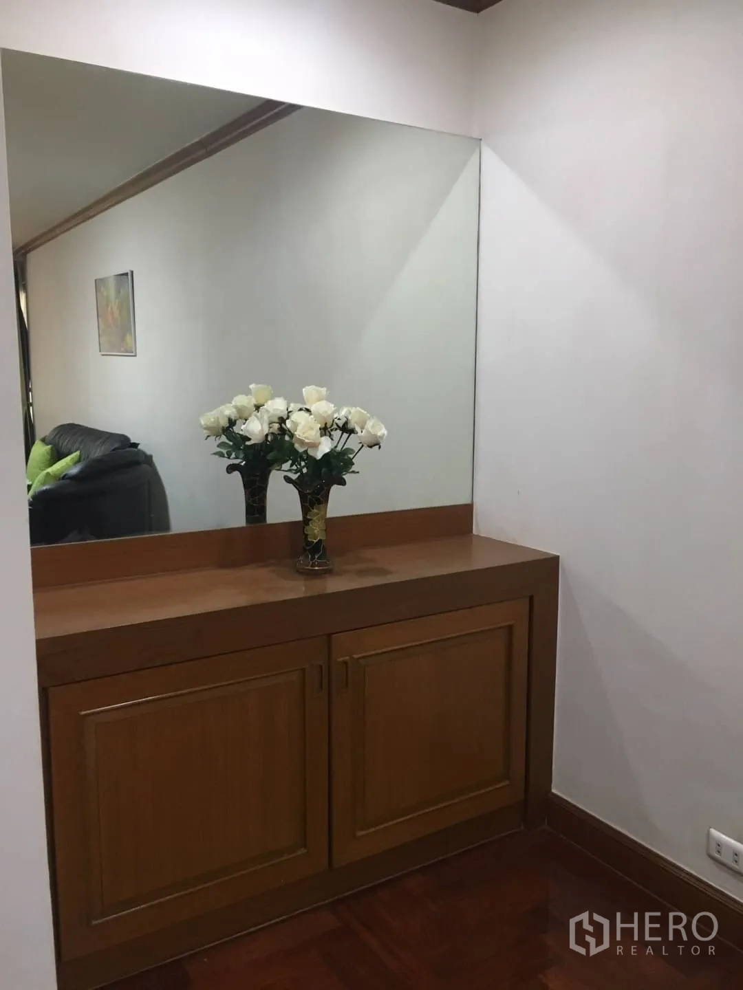 Condominium for rent in Watthana, Bangkok - Entry console with large wall mirror and wooden cabinet topped with a vase of white flowers