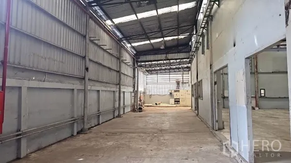 工厂 出租在Pak Kret, Nonthaburi - 服务通道，金属板墙体与可见管线，尽头为电控区，屋面带采光。