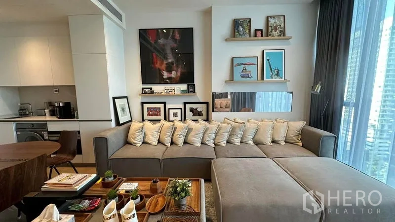Condominium for sale - Open‑plan living with large sectional sofa and compact kitchen in Thonglor condo.