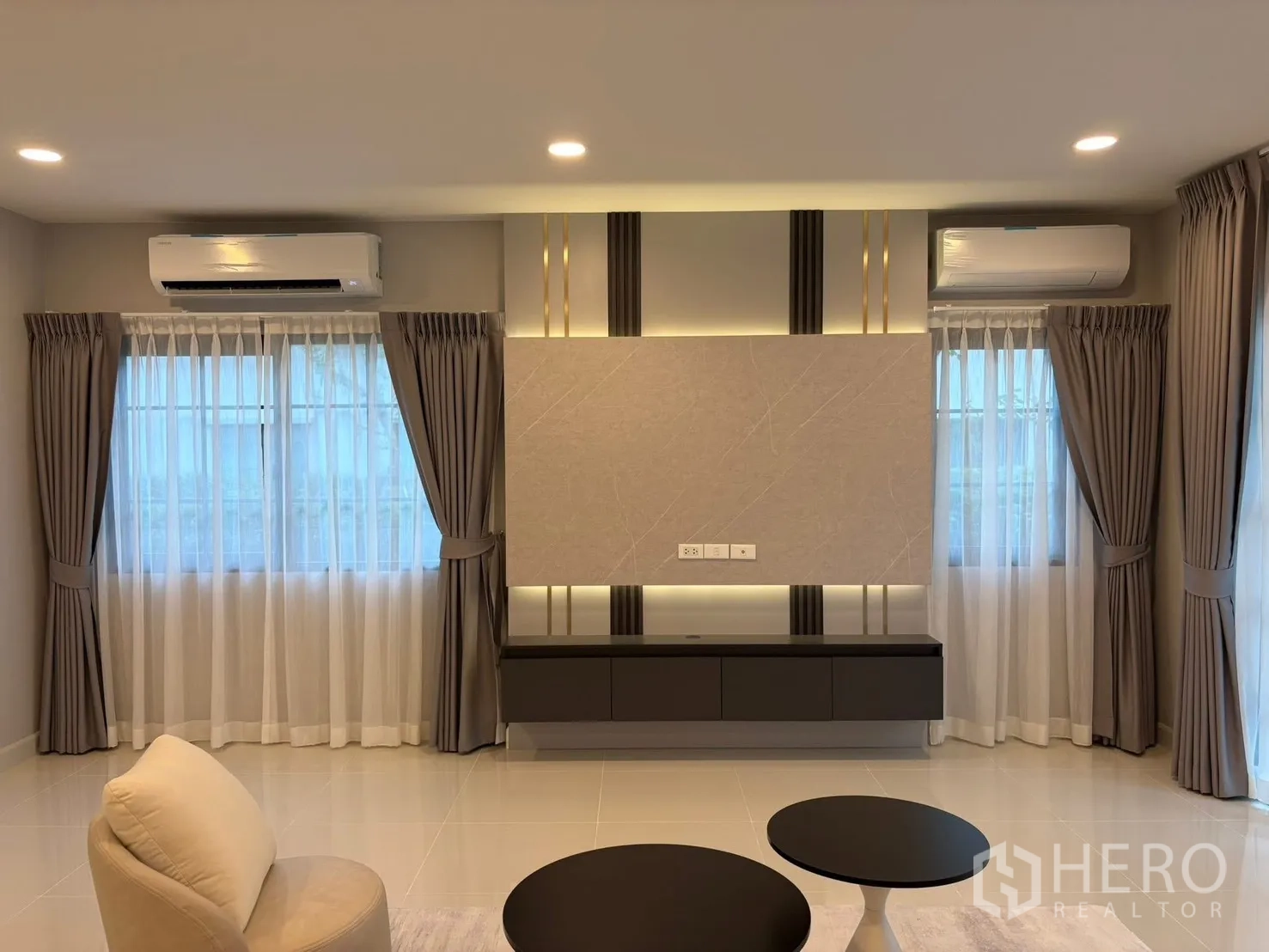 Detached House for rent in Bang Phli, Samut Prakan - Living area with TV console wall, two curtained windows, accent lighting and dual air conditioners.