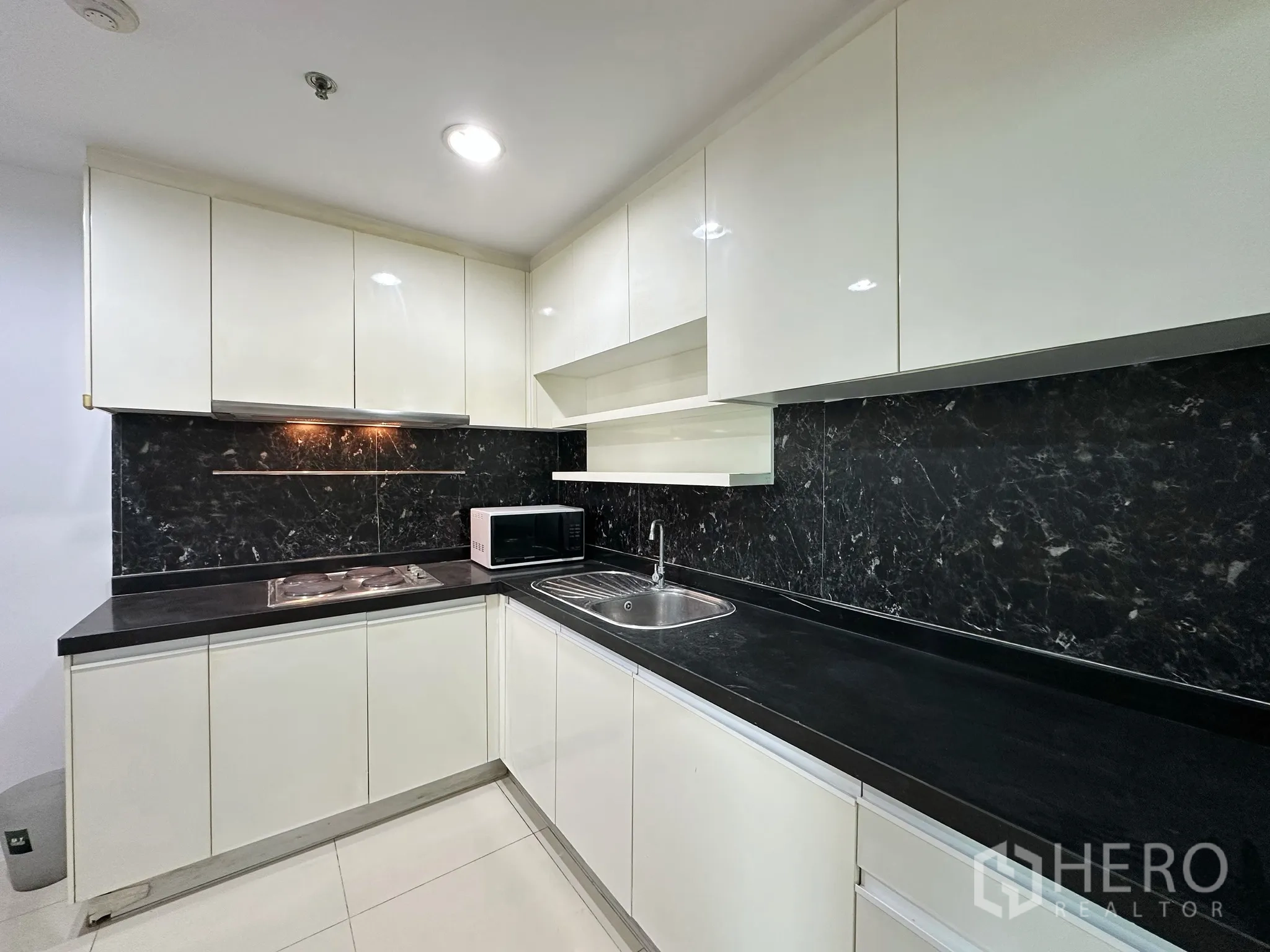 คอนโด for sale in Huai Khwang, Bangkok - ครัวแยกสไตล์ตัว U พร้อมตู้บิ้วท์อิน ผนังลายหินสีดำ ซิงก์ เตา และไมโครเวฟ.