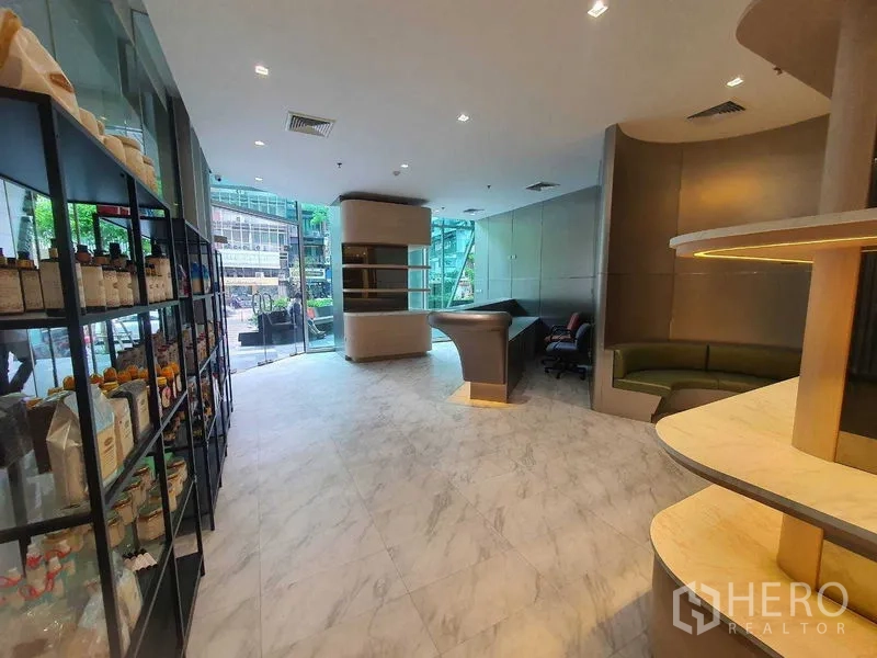 零售空间 出租在Bang Rak, Bangkok - 现代零售空间，落地玻璃门面、仿大理石地面、货架与弧形柜台。