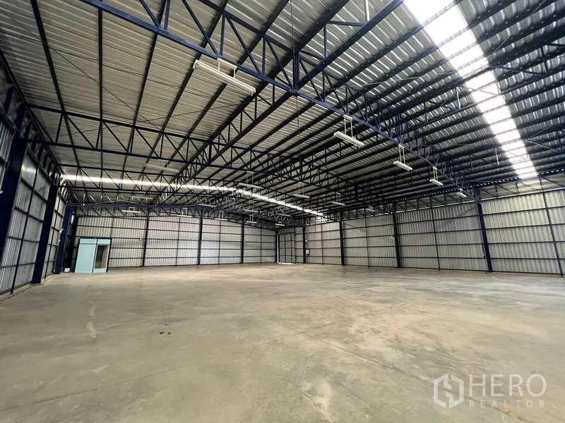 Warehouse for rent in Lat Krabang, Bangkok - Wide warehouse floor with metal wall panels, hanging lights and ventilation panels.