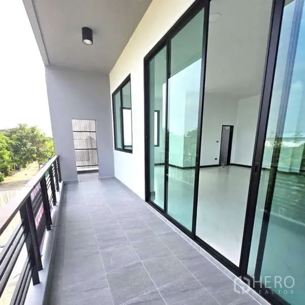 คลังสินค้า ขายในLam Luk Ka, Pathum Thani - ระเบียงชั้นบนปูพื้นกระเบื้องเทา พร้อมประตูกระจกบานเลื่อนเข้าสู่ออฟฟิศโปร่งสว่าง