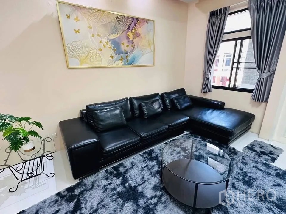 联排别墅 for rent - 客厅配黑色L形真皮沙发、玻璃圆几与地毯。