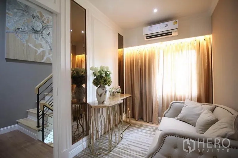 บ้าน ให้เช่าหรือขายในLat Phrao, Bangkok - พื้นที่นั่งเล่นชั้นบน โซฟาเล็ก โต๊ะคอนโซลตกแต่ง และบันได แสงอบอุ่นจากผ้าม่าน