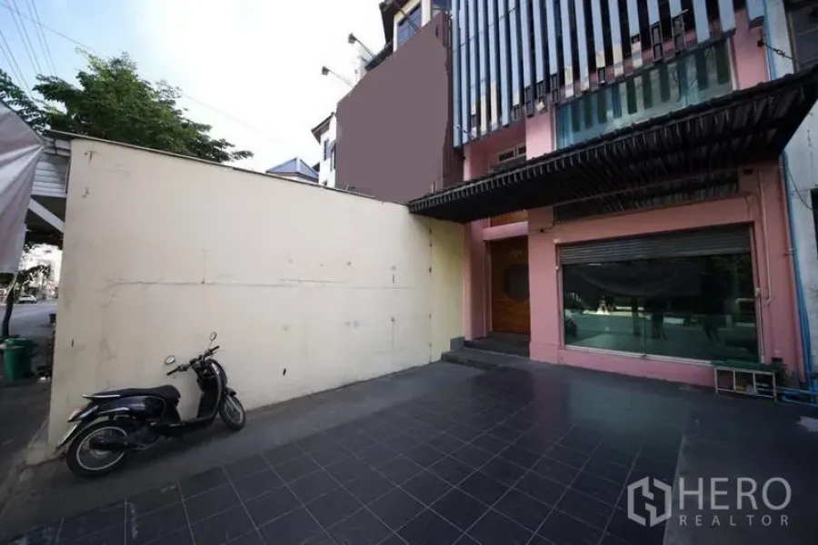 สำนักงานที่บ้าน ให้เช่าหรือขายในHuai Khwang, Bangkok - ลานหน้าบ้านปูพื้นกระเบื้องพร้อมที่จอดรถ และด้านหน้าโฮมออฟฟิศกระจกในย่านห้วยขวาง กรุงเทพฯ