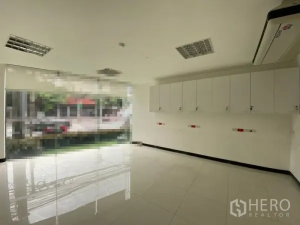 零售空间 出租 - 曼谷瓦塔那明亮商铺内景，落地玻璃、壁柜与瓷砖地面。