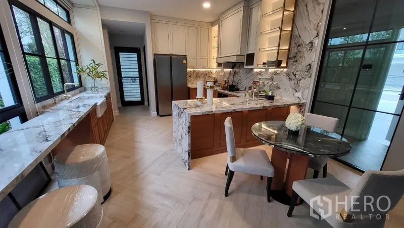 Detached House for rent or sale in Saphan Sung, Bangkok - Gourmet kitchen featuring marble island, built-in cabinetry and a casual dining table.