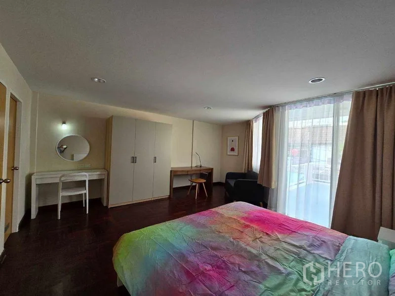 ทาวน์เฮาส์ ให้เช่าในBang Na, Bangkok - มุมห้องนอนหลักเห็นตู้เสื้อผ้า โต๊ะเครื่องแป้ง และประตูกระจกออกระเบียง