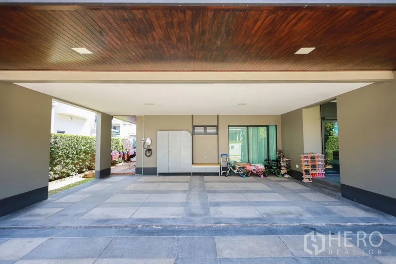 Detached House for rent or sale in Lam Luk Ka, Pathum Thani - Open carport area with tiled floor, storage cabinet and EV charger.