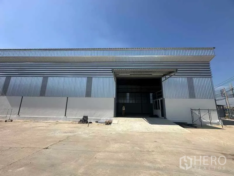 Warehouse for rent in Bang Bua Thong, Nonthaburi - Modern metal-clad warehouse facade with large roller shutter and wide concrete forecourt.