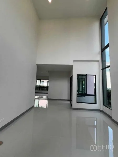 Detached House for rent in Khlong Sam Wa, Bangkok - Double-height interior hall featuring tall windows and minimalist white walls.