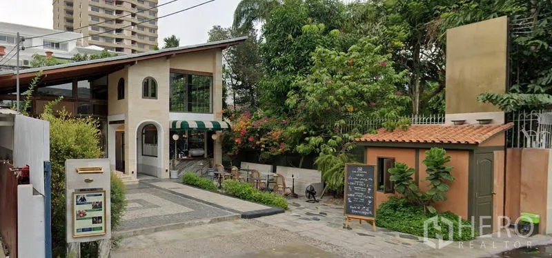 零售空间 出租在Khlong Toei, Bangkok - 物业广角图：庭院带室外座位、条纹遮阳篷、小型亭屋与成树，沿车道入口。