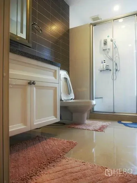 独立式住宅 出租或出售在Pak Kret, Nonthaburi - 现代卫浴，玻璃淋浴间、白色洗手台、坐便器与棕色墙砖。