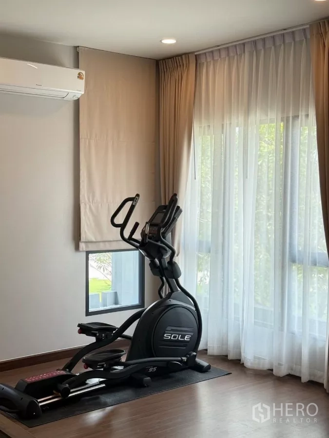 Detached House for rent in Bang Phli, Samut Prakan - Sunlit multipurpose room staged as a home gym with an elliptical machine.