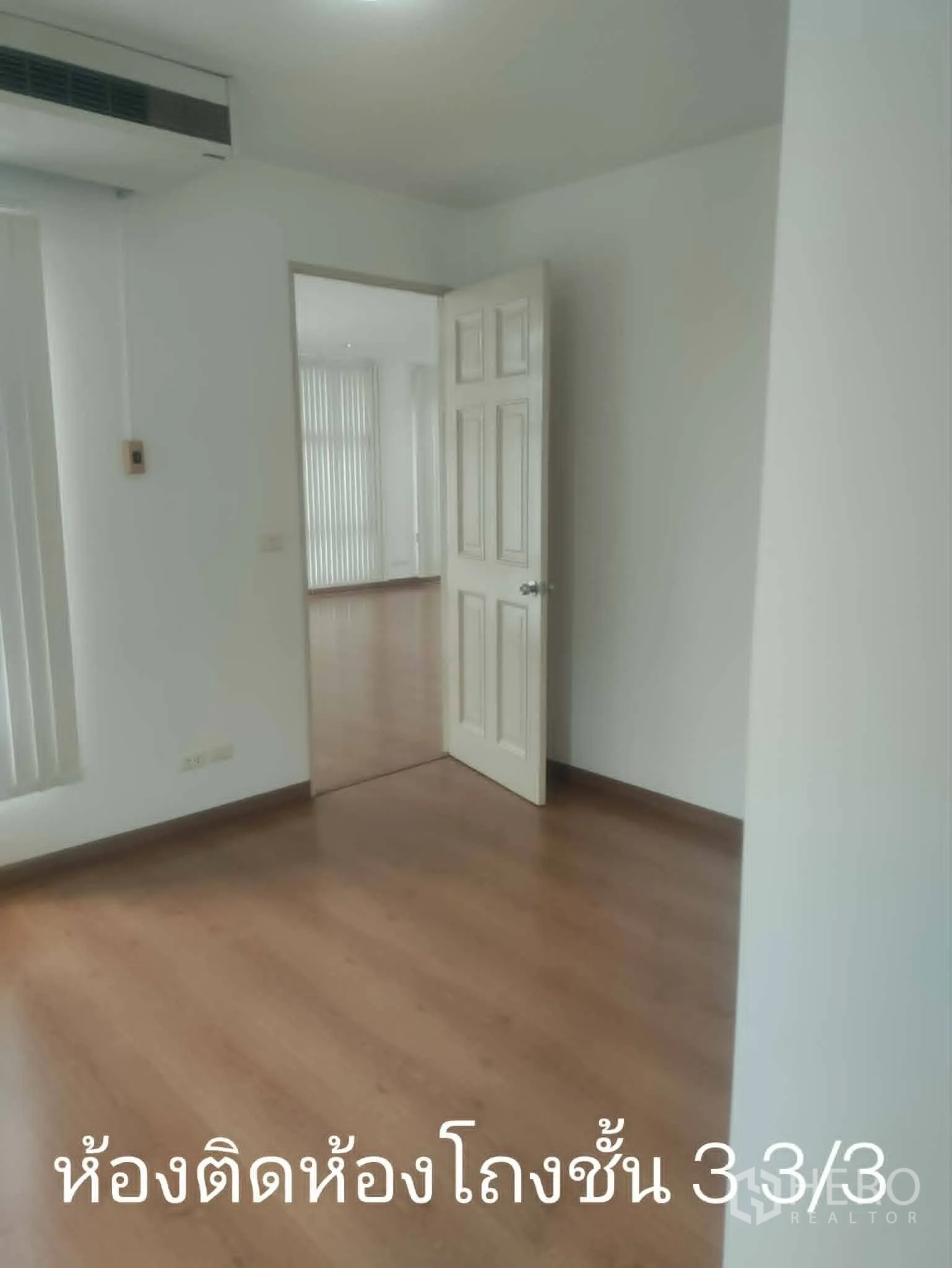 Home Office for rent in Lat Phrao, Bangkok - Small room adjoining a larger space with wood floors and white walls.