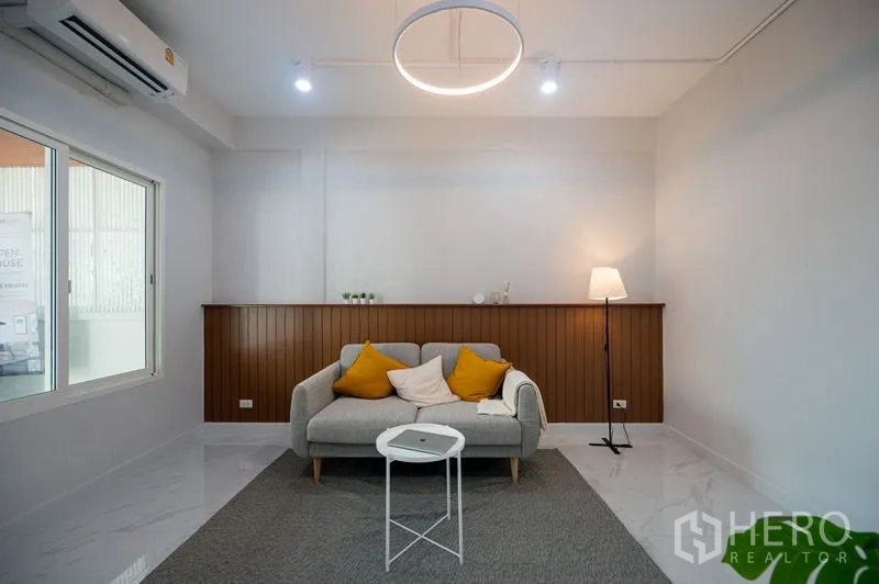 Townhouse for sale in Din Daeng, Bangkok - Minimalist living space with ring ceiling light and feature wall paneling.