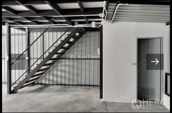 Warehouse for rent in Bangkok - Close view of the steel staircase leading to the mezzanine beside a utility room inside the warehouse.
