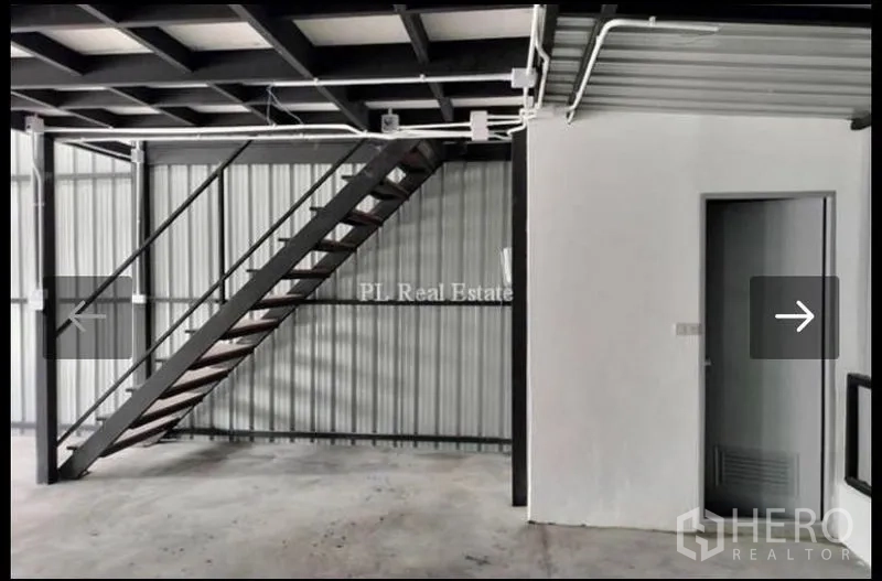 Warehouse for rent in Bangkok - Close view of the steel staircase leading to the mezzanine beside a utility room inside the warehouse.