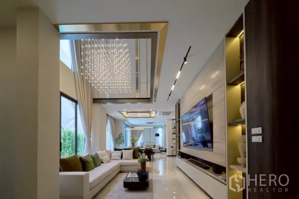 บ้าน ขายในLat Phrao, Bangkok - ห้องนั่งเล่นแบบเปิดโล่ง โซฟาเข้ามุม ผนังทีวีขนาดใหญ่ และโคมระย้าแวววาว