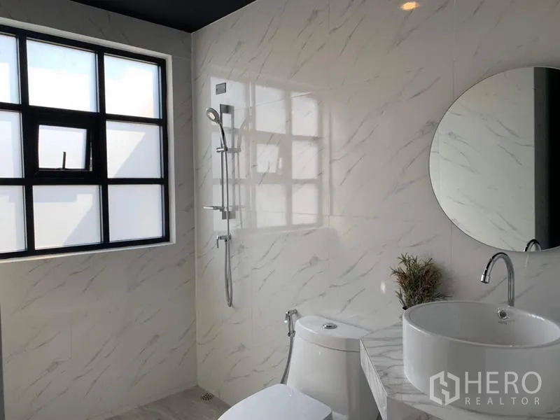 联排别墅 出租在Bang Kapi, Bangkok - 明亮卫浴，通体仿大理石墙面，圆镜、台上盆与淋浴区。