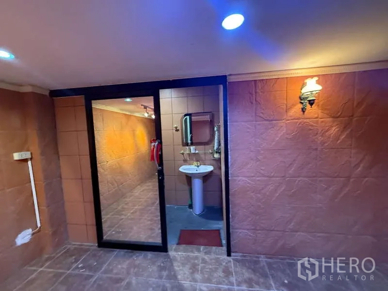 Home Office for rent in Khlong Toei, Bangkok - Restroom area with pedestal sink behind a sliding glass partition inside the workspace.