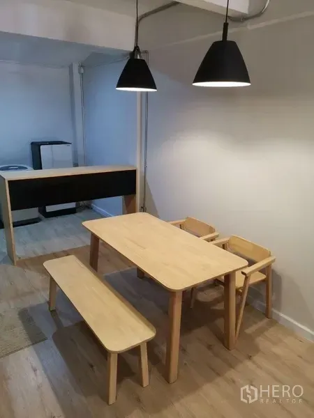 Townhouse for rent in Din Daeng, Bangkok - Minimal dining area featuring a wooden table, bench seating and black pendant lights.