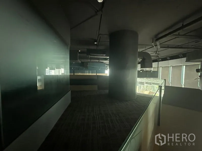 Office Space for rent - Mezzanine walkway with dark ceiling and carpet overlooking the open office and exterior glazing.