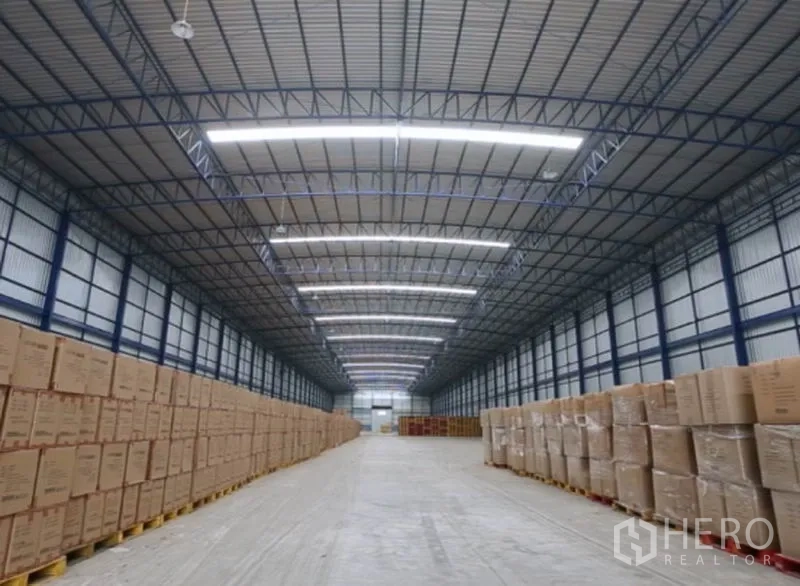 Warehouse for rent in Lat Lum Kaeo, Pathum Thani - Long warehouse aisle with palletised cartons under LED skylights and a steel roof.