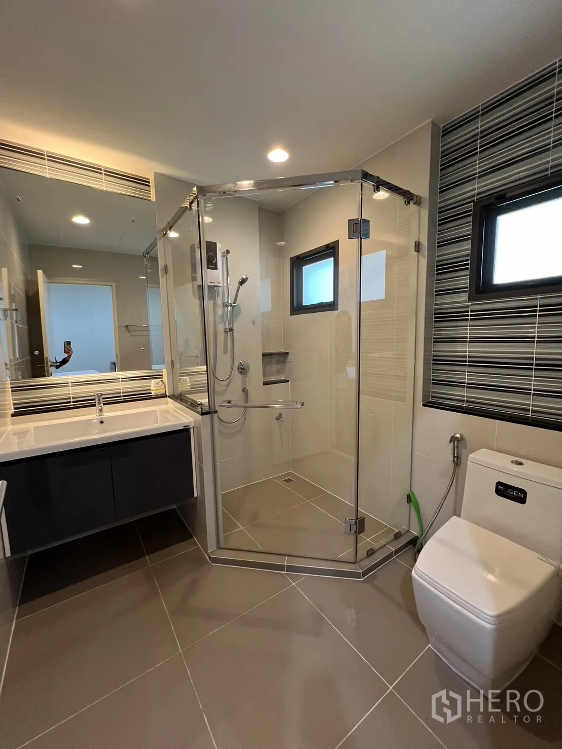 Detached House for rent or sale in Bang Kapi, Bangkok - Bathroom with frameless glass shower, vanity and striped feature tiles.