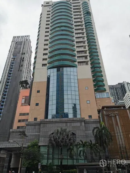 Condominium for rent in Watthana, Bangkok - High-rise exterior of Las Colinas condo with curved green balconies and a glass facade.