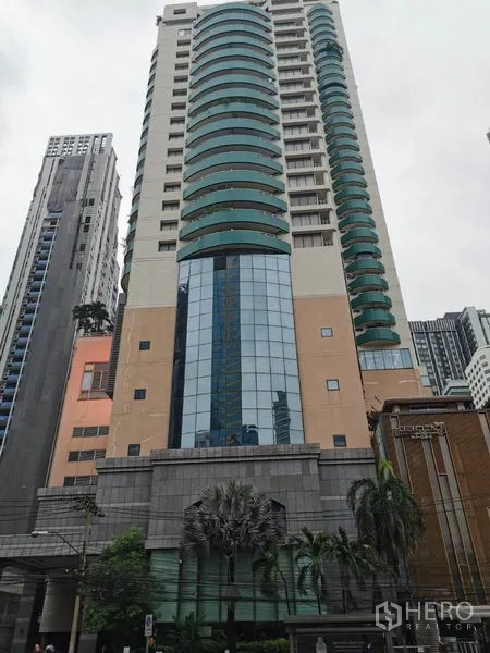 Condominium for rent in Watthana, Bangkok - High-rise exterior of Las Colinas condo with curved green balconies and a glass facade.