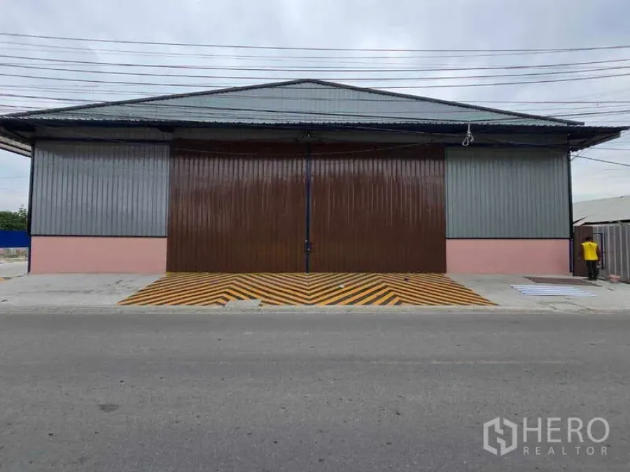 คลังสินค้า ให้เช่าในKhlong Toei, Bangkok - ด้านหน้าโกดัง ประตูสไลด์เหล็กปิดสนิท พร้อมทางลาดความปลอดภัยลายเหลืองดำ