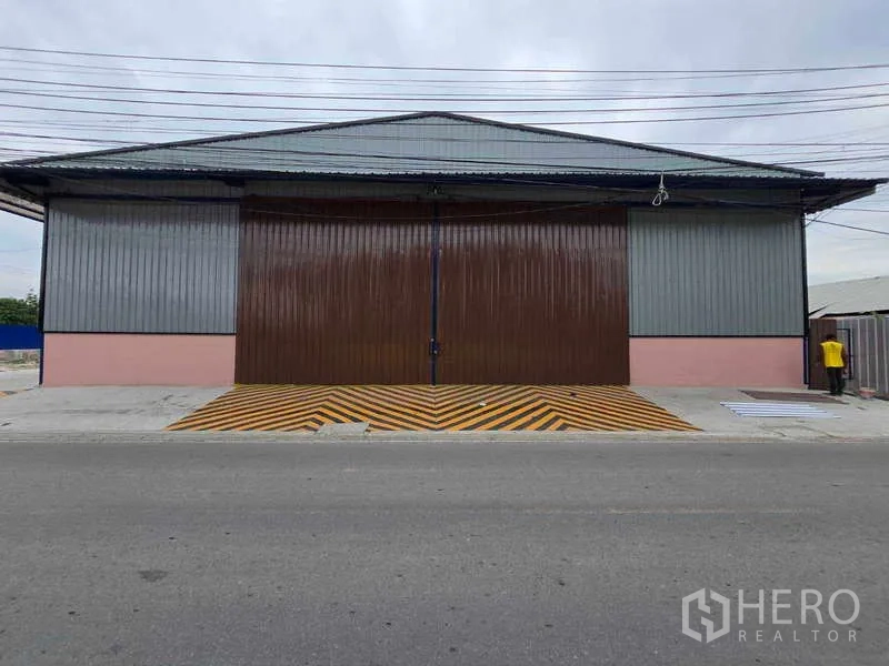 คลังสินค้า ให้เช่าในKhlong Toei, Bangkok - ด้านหน้าโกดัง ประตูสไลด์เหล็กปิดสนิท พร้อมทางลาดความปลอดภัยลายเหลืองดำ