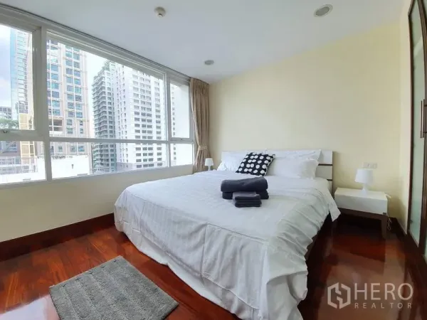 Condominium for rent or sale in Pathum Wan, Bangkok - Bright master bedroom with large corner windows, city views and polished wooden floors.
