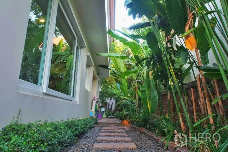 独立式住宅 出租或出售在Pak Kret, Nonthaburi - 侧院步道，卵石与踏步交错，两侧热带植物成荫。
