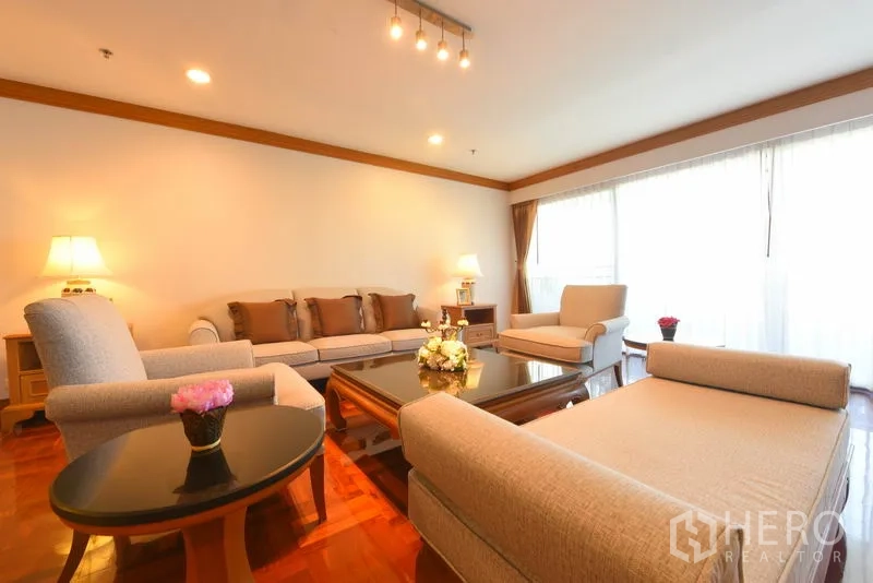 อพาร์ทเมนท์ ให้เช่าในWatthana, Bangkok - ห้องนั่งเล่นสว่างด้วยโซฟาสีครีม โต๊ะกลาง หน้าต่างบานใหญ่ และพื้นปาร์เกต์เงางาม