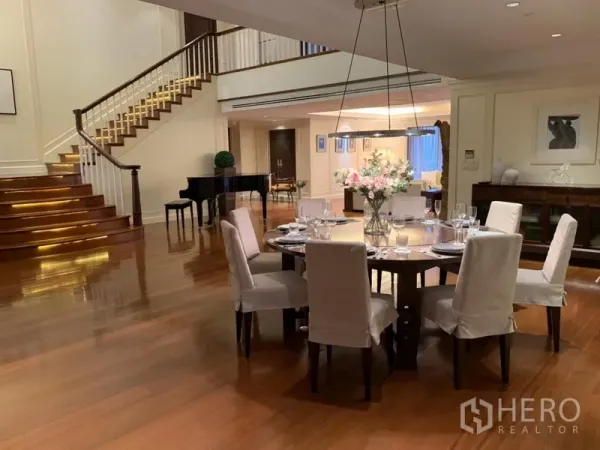 Condominium for rent or sale in Watthana, Bangkok - Elegant dining area with a round table for eight beside a feature staircase and piano.
