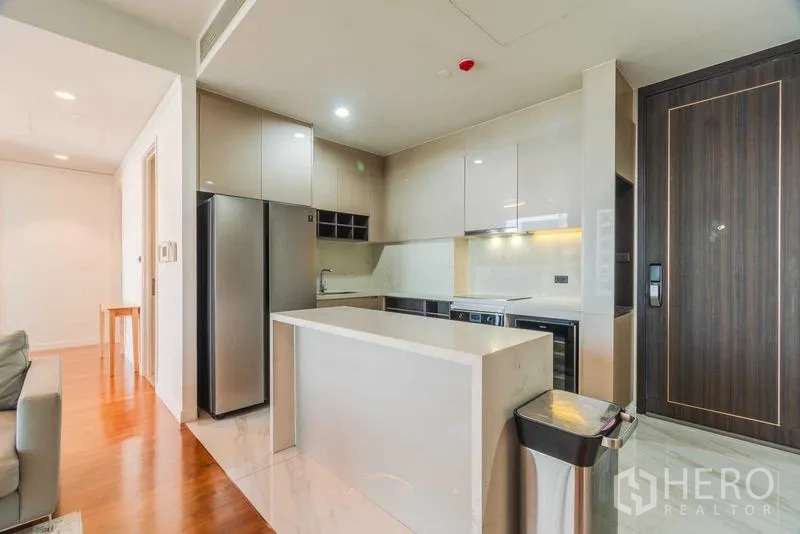 Condominium for rent or sale - Entry view to a sleek kitchen with an island and tall wooden door.