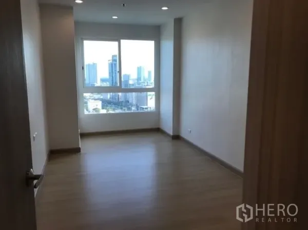 Condominium for sale in Yan Nawa, Bangkok - Spacious bedroom with wood flooring and a large window showcasing Bangkok skyline views.