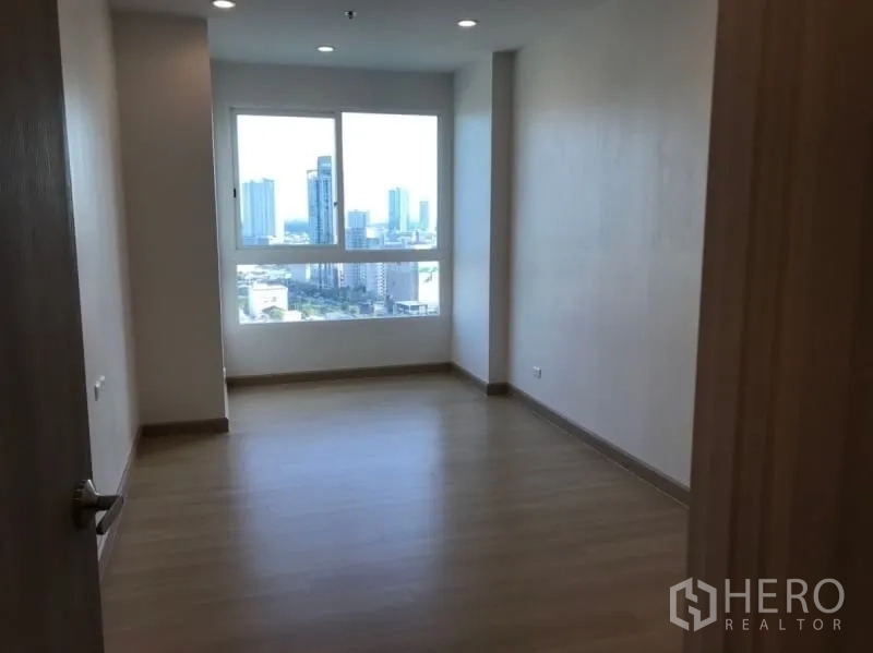 Condominium for sale in Yan Nawa, Bangkok - Spacious bedroom with wood flooring and a large window showcasing Bangkok skyline views.