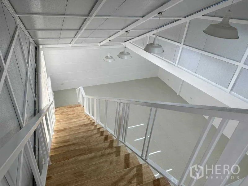 Office Space for rent or sale in Khlong Toei, Bangkok - Downward view along wooden-tread stairs with white railings and industrial lights.