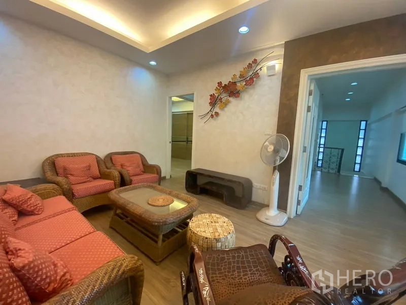 Detached House for sale in Khlong Toei, Bangkok - Family lounge with rattan sofa set, feature wall art, and warm ceiling lights.
