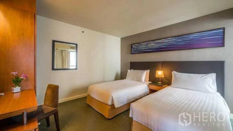 Condominium for rent in Bang Kho Laem, Bangkok - Twin bedroom with two single beds, a desk and warm wood cabinetry.