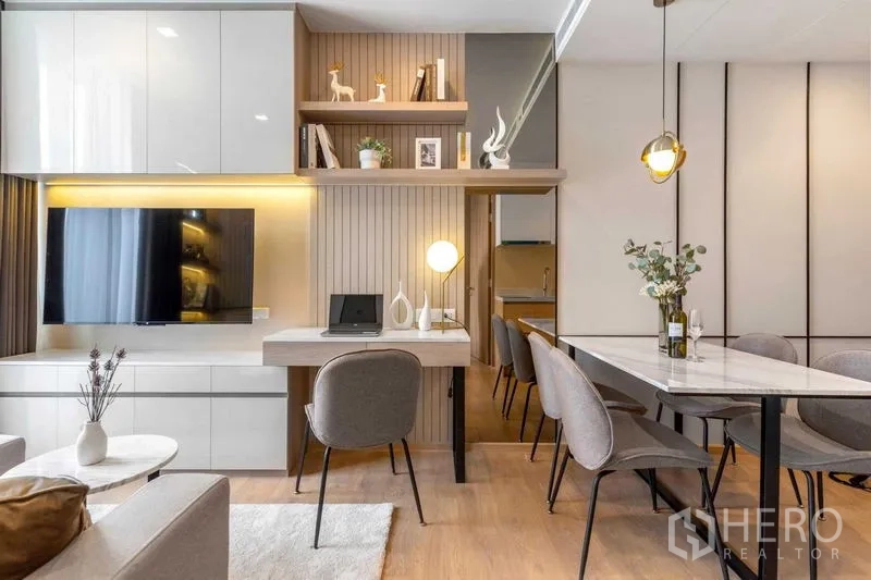 Condominium for rent in Watthana, Bangkok - Built-in TV wall, shelving and a work desk beside the dining area with a pendant light.