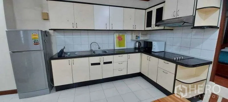 คอนโด ให้เช่าในKhlong Toei, Bangkok - ครัวรูปตัวแอล ตู้สีขาว ท็อปสีดำ เตา เครื่องดูดควัน ตู้เย็น และไมโครเวฟ