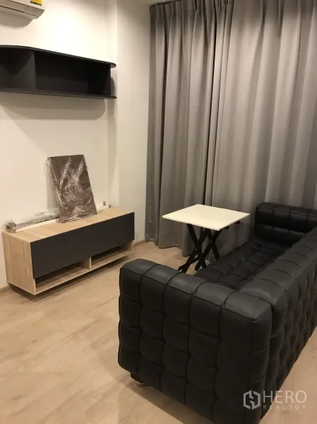 公寓 出租或出售在Ratchathewi, Bangkok - 舒适客厅，黑色绗缝沙发、电视柜、壁架与全高遮光窗帘