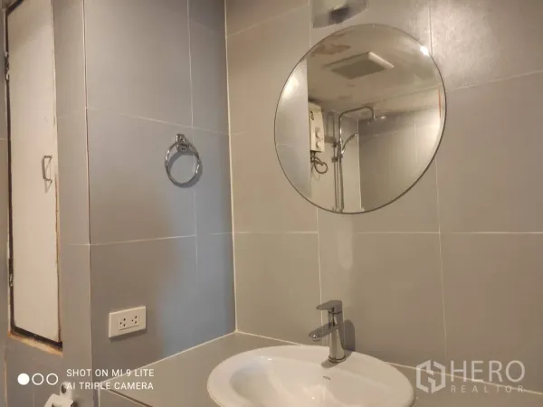 อพาร์ทเมนท์ ให้เช่าในWatthana, Bangkok - ห้องน้ำกระจกเงากลม อ่างล้างหน้าเซรามิก และผนังกระเบื้องสีเทา